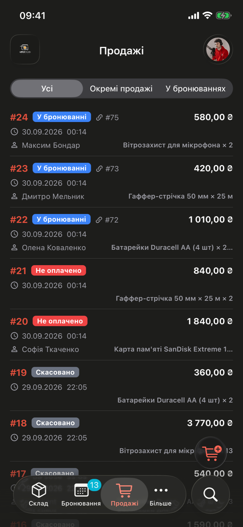 The Sales tab of the iOS app in the Ukrainian interface. Chips at the top read All, Standalone sales and On bookings. Each row shows the sale number in red, a state tag such as On booking in blue, Unpaid in red or Cancelled in grey, a link to the booking number, the date and time, the client, the items and the total in hryvnias. A cart button with a plus floats above the tab bar, which holds Inventory, Bookings, Sales and More